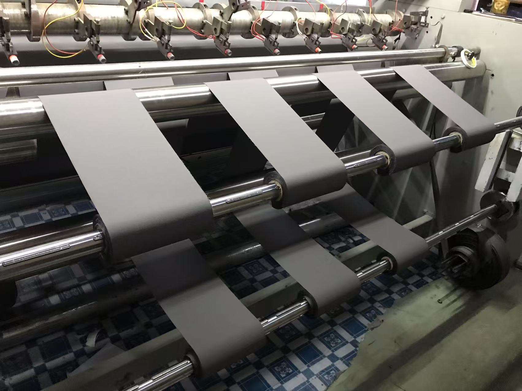 Real grey coated fabric strips running through production equipment